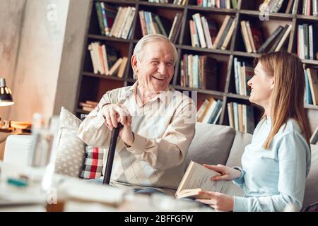Padre e figlia in casa biblioteca seduta ridendo su divertente storia allegro Foto Stock