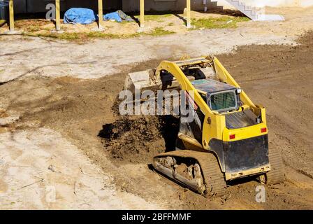 Mini bulldozer lavora con la terra mentre facendo lavori di ingegneria naturalistica sulla costruzione di suolo in movimento Foto Stock