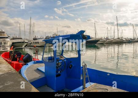 Vista sul porto turistico di Sanremo con un blu e un rosso motoscafi ormeggiati su un molo e una fila di yacht di lusso sullo sfondo, Liguria, Italia Foto Stock