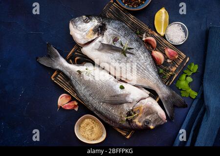 Due pesci dorado e ingredienti su un tagliere e. sfondo blu Foto Stock