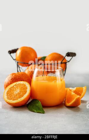 Succo d'arancia fresco in un bicchiere e arance alla luce sfondo Foto Stock