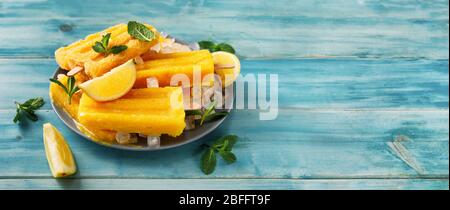 Il sorbetto al mango vegano popsicles su sfondo turchese alla moda Foto Stock