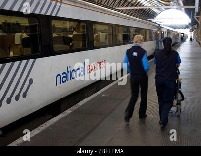 La gente passa con un treno National Express alla stazione di Kings Cross, Londra. Foto Stock