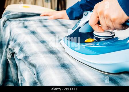 Primo piano mano uomo stiratura camicia. Foto Stock