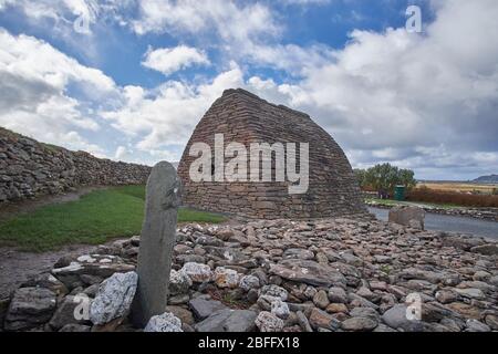 Vista esterna sul Gallarus Oratory nella contea di Dingle Peninsula Kerry Irlanda mostrando la pietra di Colum Mac Dinet in primo piano. Foto Stock