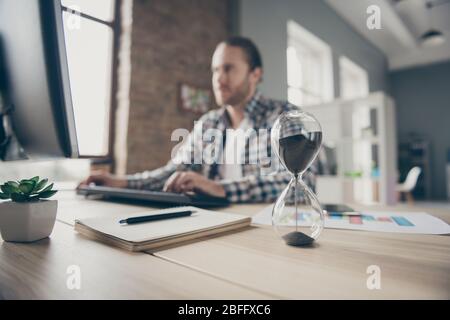 Sfocata foto fuoco di bel business ragazzo guardare computer orologio di sabbia monitor sul tavolo chiacchierando boss promessa finale rapporto in tempo indossare camicia casual Foto Stock