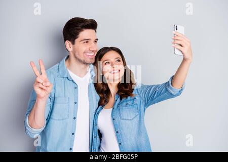 Foto di bella donna coppia di tipo in amore tenere telefono facendo selfie mostrando simbolo di amicizia v indossare casual jeans camicie vestito Foto Stock