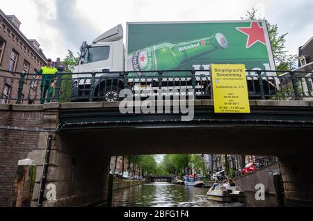 Un camion Heineken che aspetta su un ponte sospeso come visto mentre navighi nel canale Singelgracht in un pomeriggio coperto ad Amsterdam, Paesi Bassi Foto Stock