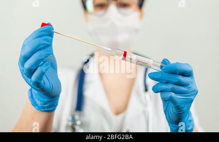 Test per il coronavirus Covid-19. Medico o infermiere che esegue analisi di laboratorio di un tampone nasale in un laboratorio ospedaliero. Tecnico medico che tiene un kit di strisci COVID-19, indossando guanti di protezione da Foto Stock