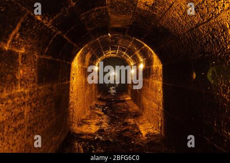 Vecchia volta inondato intorno tunnel sotterraneo fognario con acqua sporca fognaria Foto Stock