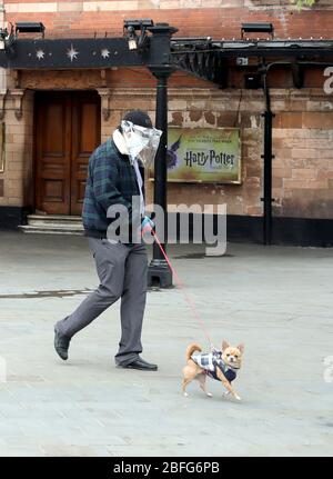 Londra, Regno Unito. 18 Aprile 2020. Giorno ventisei di Lockdown a Londra. Un uomo, in maschera facciale e guanti, cammina il suo cane oltre il Palace Theatre che avrebbe dovuto mostrare Harry Potter e il bambino maledetto. Il paese è bloccato a causa della pandemia di Coronavirus COVID-19. La gente non è autorizzata lasciare la sede tranne per shopping di alimento minimo, trattamento medico, esercitazione - una volta al giorno e lavoro essenziale. COVID-19 Coronavirus lockdown, Londra, Regno Unito, il 18 aprile 2020 Credit: Paul Marriott/Alamy Live News Foto Stock