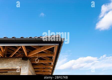 Il tetto di una casa singola-familiare coperta con una nuova piastrella in ceramica antracite contro il cielo blu, capriate visibili. Foto Stock