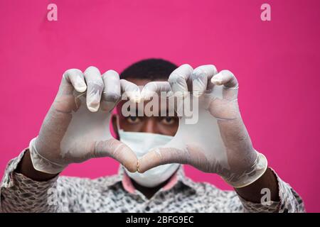 un giovane medico africano isolato su sfondo rosa indossando maschera facciale per prevenire, prevenire, si è impedito dallo scoppio nella società e. Foto Stock