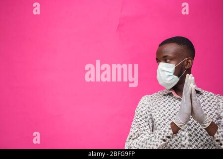 un giovane medico africano isolato su sfondo rosa indossando maschera facciale per prevenire, prevenire, prevenire se stesso dallo scoppio nella società e. Foto Stock