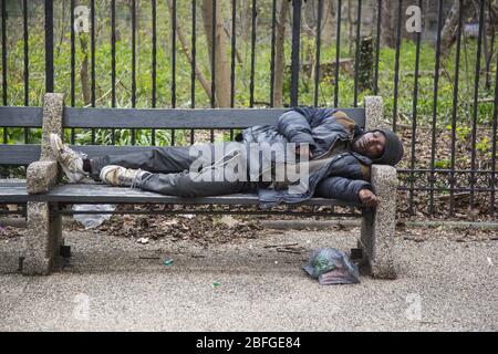 I senzatetto dorme su una panchina lungo Parkside Avenue durante la pandemia di Coronavirus a Brooklyn, New York. Foto Stock