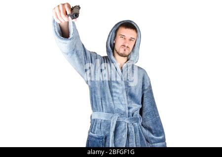 Ritratto del giovane uomo caucasico bearded in accappatoio blu con arma da fuoco nera isolata su sfondo bianco. Concetto di emozione Foto Stock