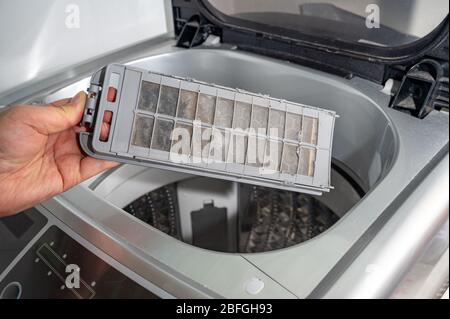 Polvere e sporcizia intrappolate dal filtro della lavatrice. Foto Stock