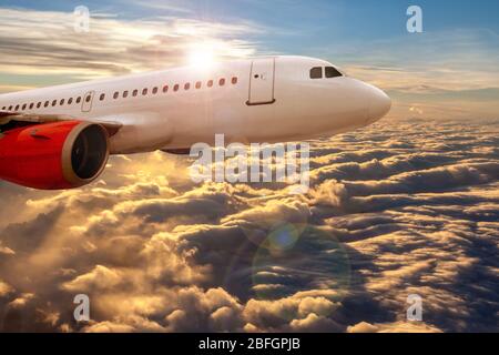 Concetto di aviazione che mostra la vista di un aereo che vola sopra le nuvole dorate del tramonto con spazio copia. Concetto di viaggio aereo per affari o piacere. Foto Stock