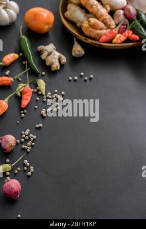 Ingredienti di base di condimento in un piatto di legno. Alcune spezie fotografate sparse su uno sfondo nero. Foto Stock