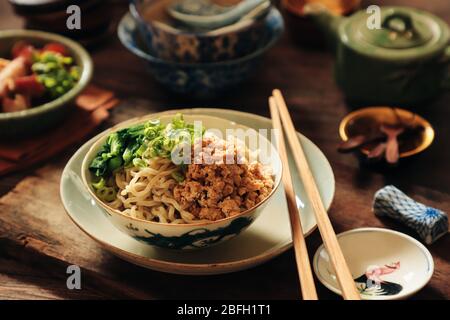 Uova Noodles con pollo tritato. Un alimento di base cinese di tagliatelle gialle con pollo macinato e choy sum aromatizzato alla soia; placcato su stoviglie d'epoca. Foto Stock