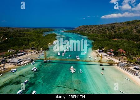 Vista aerea di un ponte che collega due isole tropicali su uno stretto canale oceanico (Nusa Lembongan e Nusa Ceningan, Indonesia) Foto Stock