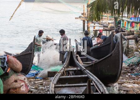 Kochi, Kerala - 30 dicembre 2019: I pescatori che minacciano le loro reti accanto alle loro barche da pesca in Fort kochi, kerala india Foto Stock