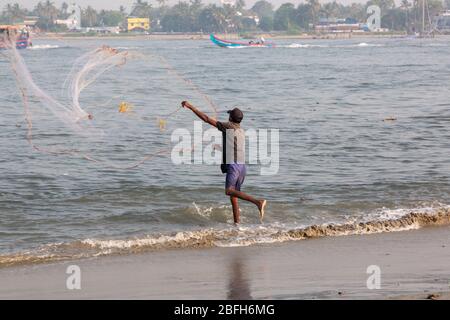 Kochi, Kerala - 30 dicembre 2019: Pescatore che gettò la sua rete dal forte spiaggia kochi, kerala india Foto Stock