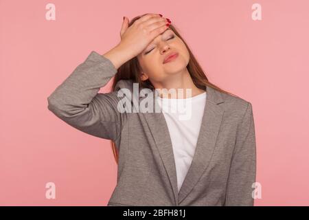 Facepalm. Ritratto di perdonata sconvolgente giovane donna in tuta aziendale toccando la fronte con espressione dolorosa, incolpando per fallimento, cattiva memoria. io Foto Stock