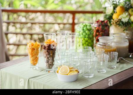 Gli spuntini sono serviti sul tavolo fianco a fianco con un bicchiere vuoto e fette di limone. Foto Stock