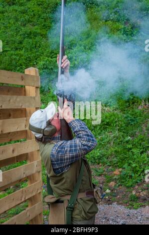 Un'antica pistola di blocco della selce che è sparata da un uomo durante una competizione di tiro del piccione di argilla Foto Stock