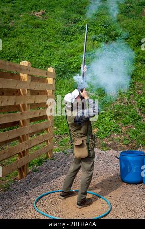 Un'antica pistola di blocco della selce sparata da un uomo durante una competizione di tiro al piccione di argilla (nota: Questo è il numero 3 in una serie di 6 colpi che mostrano il fumo dalla pistola durante il tiro) Foto Stock