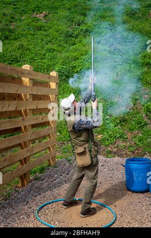 Un'antica pistola di blocco della selce sparata da un uomo durante una competizione di tiro al piccione di argilla (nota: Questo è il numero 6 in una serie di 6 colpi che mostrano il fumo dalla pistola durante il tiro) Foto Stock