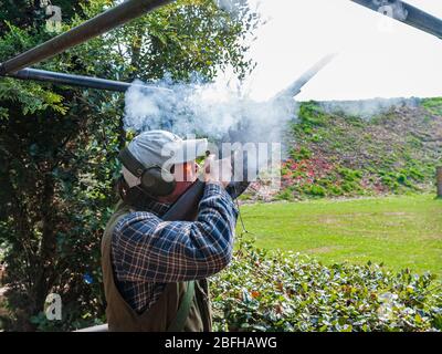 Un'antica pistola di blocco della selce che è sparata da un uomo durante una competizione di tiro del piccione di argilla Foto Stock