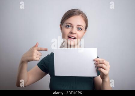 Sorridente giovane donna caucasica ragazza tenendo bianco foglio di carta con spazio per le copie Foto Stock