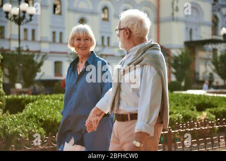 Amo mio marito. Coppia anziana felice e bella tenendo le mani e guardandosi mentre si cammina all'aperto. Famiglia. Concetto di amore Foto Stock