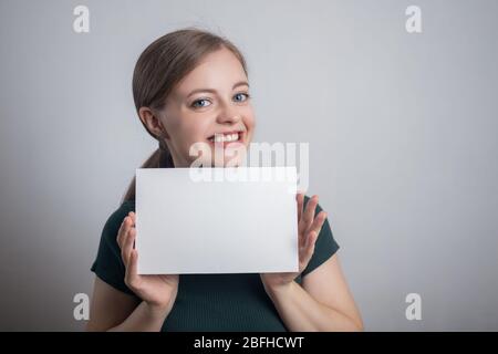 Sorridente giovane donna caucasica ragazza tenendo bianco foglio di carta con spazio per le copie Foto Stock