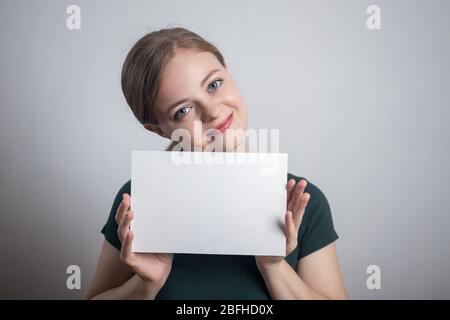 Sorridente giovane donna caucasica ragazza tenendo bianco foglio di carta con spazio per le copie Foto Stock