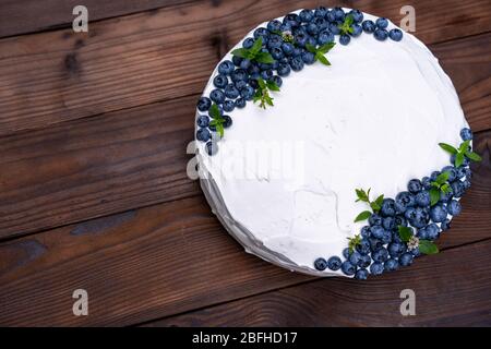 Stuzzicanti cheesecake biscotto decorato a cuscino crema bianca mirtilli e menta sorge su legno tavolo rustico. Torta dolce con il pezzo sulla piastra Foto Stock