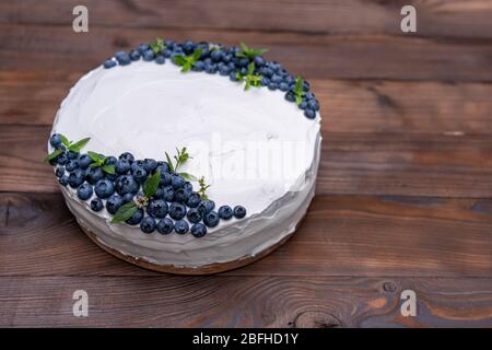 Stuzzicanti cheesecake biscotto decorato a cuscino crema bianca mirtilli e menta sorge su legno tavolo rustico. Torta dolce con il pezzo sulla piastra Foto Stock