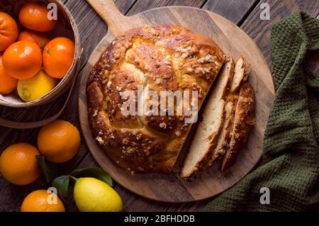 Pane dolce appena sfornato con farciture di frutta e fette di mandorla su sfondo di legno. Dessert tradizionale di Pasqua. Foto Stock