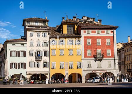 Piazza del Duomo, piazza del Duomo di Trento con le case tipiche. La gente passeggia nella piazza o si siede nei bar in una giornata di sole in inverno Foto Stock