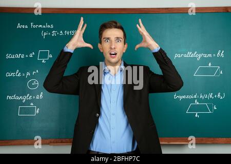 Giovane insegnante vicino a lavagna in classe scolastica Foto Stock