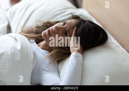 Primo piano donna infelice affetta da insonnia, sdraiata a letto Foto Stock