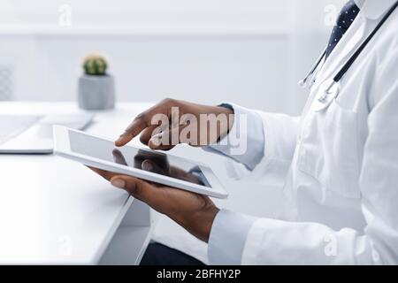 Un medico nero che utilizza un tablet digitale sul posto di lavoro Foto Stock