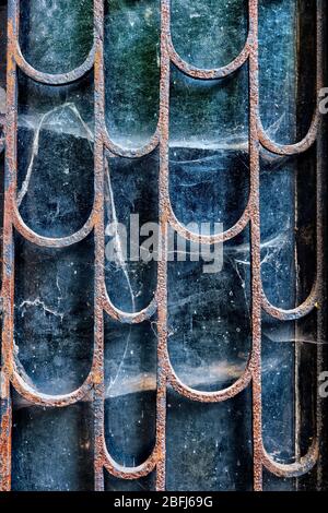 Porta ad un'antica tomba nella vecchia necropoli, ingresso spettrale coperto da ragnatele e protetto da barre di metallo arrugginite Foto Stock