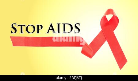 Nastro rosso AIDS su sfondo giallo Foto Stock