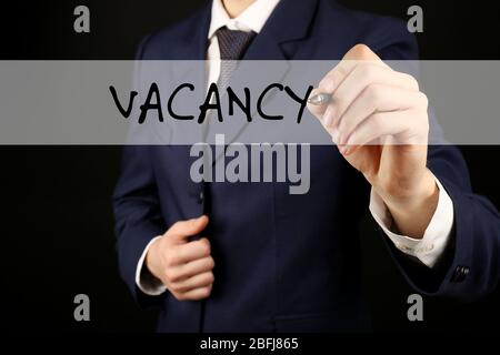 Uomo d'affari che scrive VACANCY alla lavagna trasparente, primo piano Foto Stock