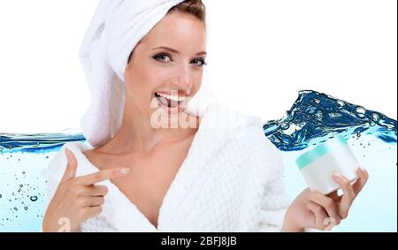 Bella giovane donna in accappatoio con crema su sfondo astratto blu acqua onda Foto Stock