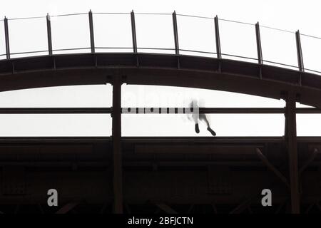 Silhouette di una persona che cammina sulla piattaforma trasparente al primo piano della Eiffel come visto dal basso, Parigi Foto Stock