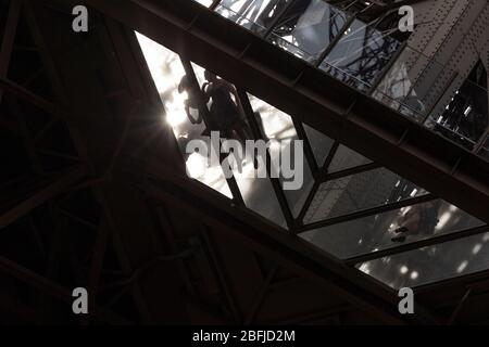 Una madre e un bambino che giacciono sulla piattaforma trasparente al primo piano della Torre Eiffel come si vede dal basso, Parigi Foto Stock